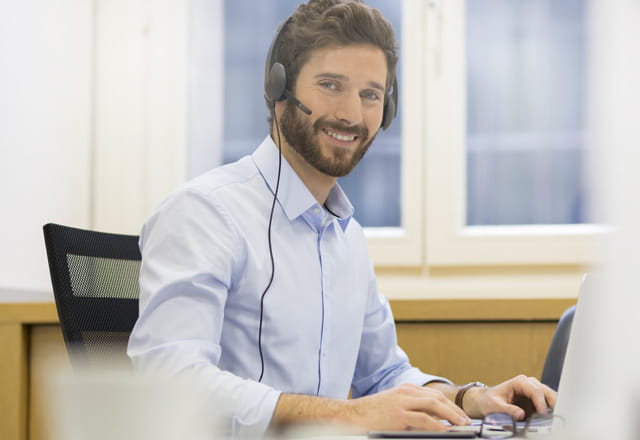 Lächelnder Mann vom Kundenservice tippt auf seinem Computer