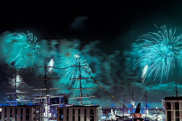 Türkises Feuerwerk erleuchtet die Schiffe und den Nachthimmel am Bremerhavener Hafen.