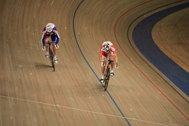 Zwei Rennradfahrer fahren in hohem Tempo auf einer Indoor-Rennradstrecke.