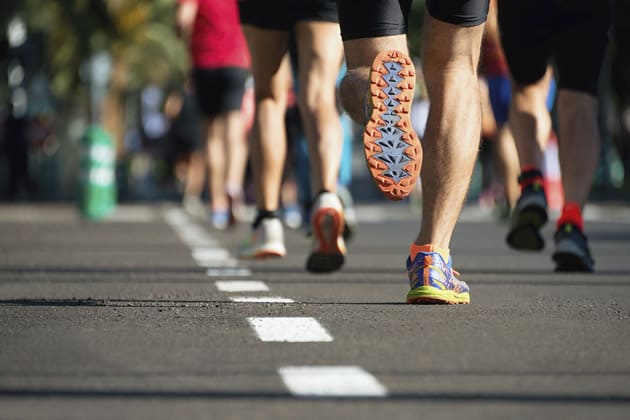 Die Beine der Laufenden, die beim swb-Marathon auf einer Straße laufen.