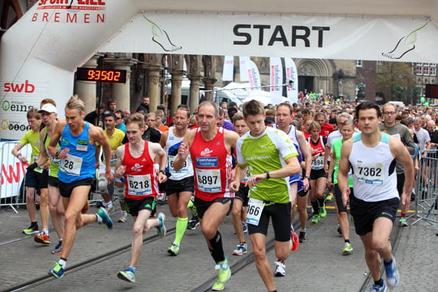 Viele sportlich gekleidete Personen am Start des Bremer swb-Marathons, wie sie gerade los laufen.