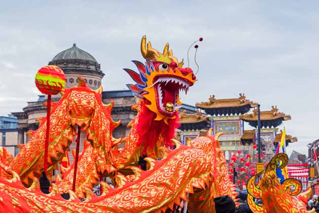 Eine orangene Drachenfigur wird zum Tanzen gebracht. Dieser sogenannte "Drachentanz" gehört zum chinesischen Frühlingsfest dazu.