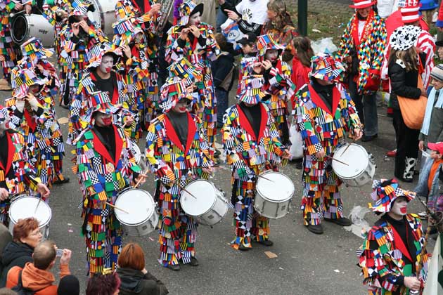Ein Karnevalsumzug mit bunt verkleideten Menschen, die auf ihren Trommeln trommeln.