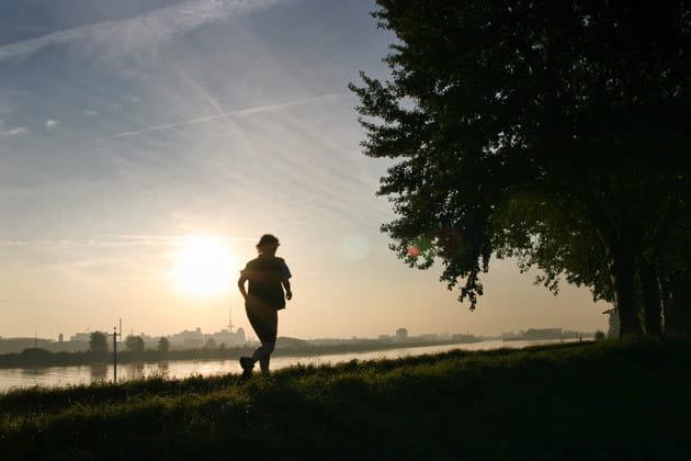 Silhouette einer Frau, die dem Sonnenaufgang am Osterdeich in Bremen entgegen joggt
