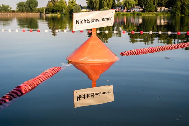 Abgesperrter Bereich in einem See mit einer orangenen Boje mit der Aufschrift "Nichtschwimmer" 