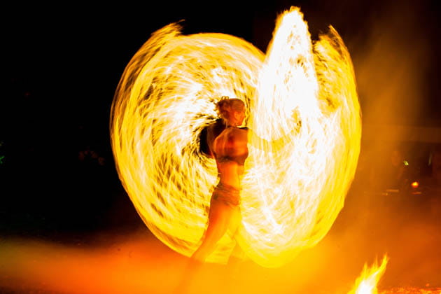 Junge Frau, die mit Feuerakrobatik eine atemberaubendes Feuererlebnis liefert