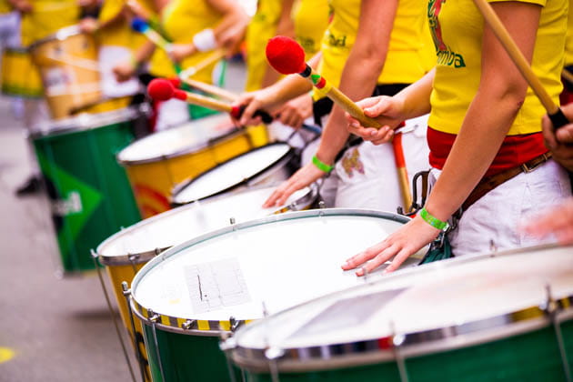 Nahaufnahme der Hände und Trommeln einer Sambagruppe, die gelbe T-Shirts tragen