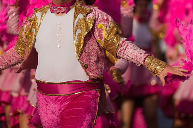 Nahaufnahme einer Person in einem Sambakostüm in leuchtendem Pink mit goldenen Applikationen