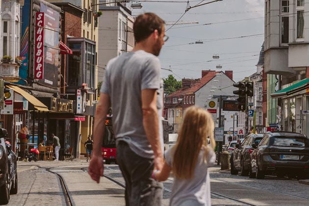Ein Mann quert mit seiner Tochter die Straße "Vor dem Steintor" im Bremer Viertel.