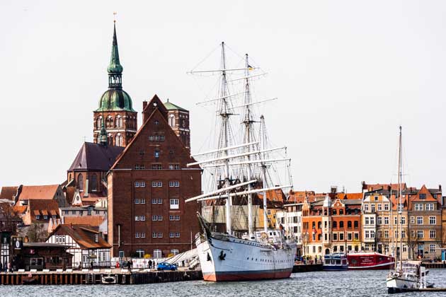 Hafen der Hansestadt Stralsund mit großem Segelschiff, das vor Anker liegt.