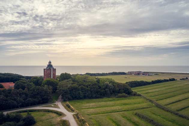 Wiesen, Wald und das Bauwerk Neuwerk auf der Hamburger Insel, welches als Leuchtturm fungiert.