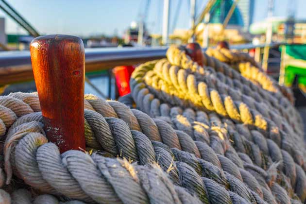 Gebundene Seile um hölzerne Bootsklampen auf einem Schiff in Bremerhaven.