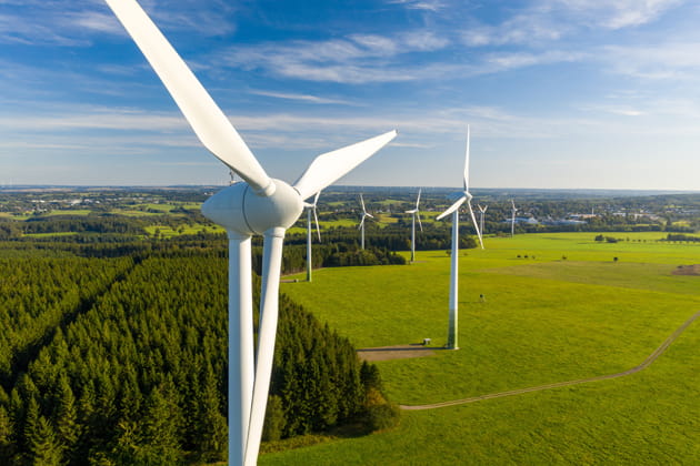 Für ein nachhaltigeres Leben erzeugen weiße Windräder zwischen Wiesen und Wald grünen Strom