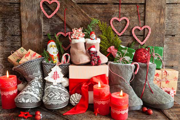 Liebevoll dekorierte Stiefel mit Weihnachtsschokolade und nachhaltigen Weihnachtsgeschenken auf einem hölzernen Untergrund