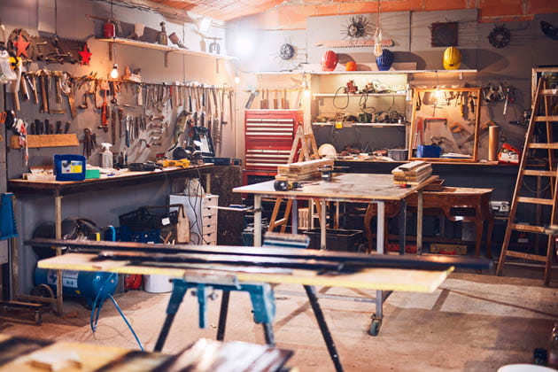Ausschnitt einer kleinen Werkstatt voller Werkzeuge an den Wänden und Werktischen in der Mitte