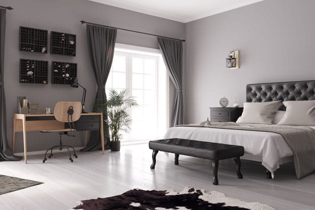 Ausschnitt einer in grau gehaltenen, minimalistischen Einrichtung eines Schlafzimmers mit Bett und Schreibtisch 