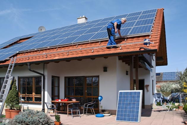 Handwerker installiert eine Solaranlage auf dem Dach eines Familienhauses