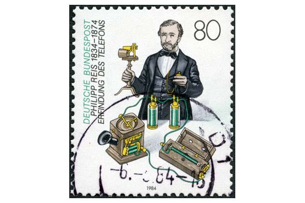 Eine alte Briefmarke, wo Phillipp Reis, der deutsche Erfinder des Telefons sowie sein Telefonapparat zu sehen sind.