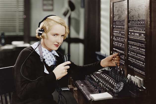 Eine blonde Dame bei der Telefonvermittlung verbindet den Anrufer und die angerufene Person.