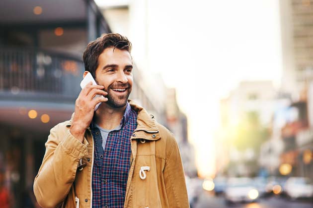 Ein Mann steht an einer Straße und hält sein Smartphone an sein Ohr.
