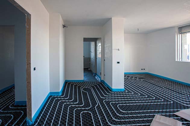 Eine fertige, mäanderförmig verlegte Fußbodenheizung in einem Neubau