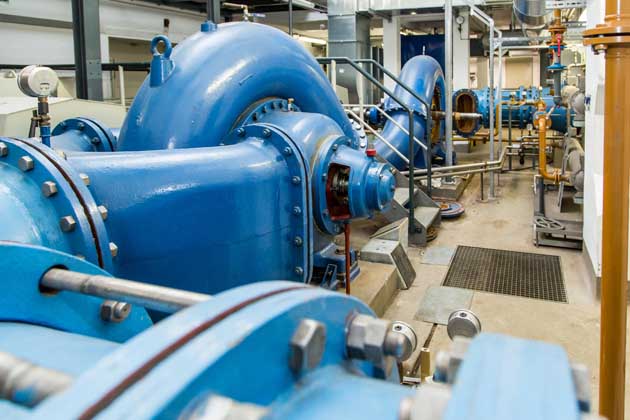 Große blaue Rohre und Pumpen in einem Wasserkraftwerk, die das frische Trinkwasser verteilen.