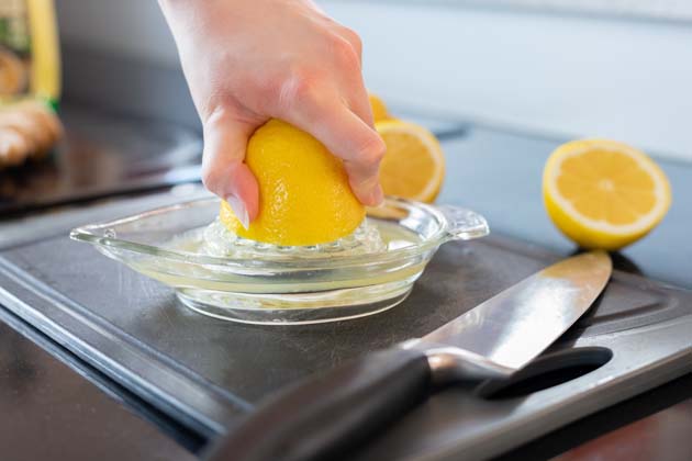Eine Zitrone auf einem Schneidebrett mit Messer wird ausgepresst.