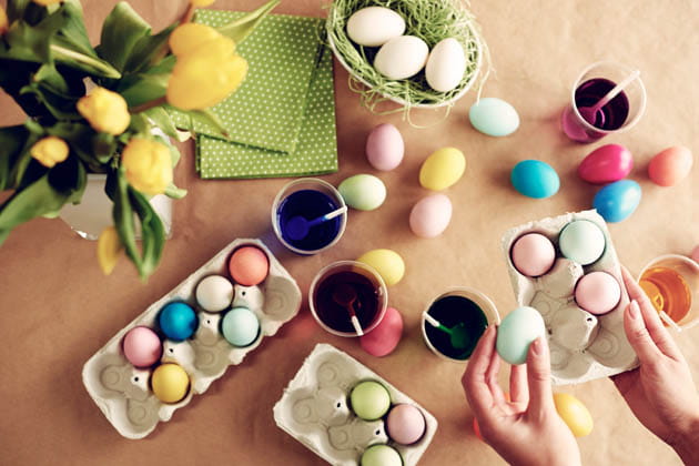 Aufnahme aus der Vogelperspektive, bei der gekochte Eier mit verschiedenen Farben gefärbt und zum Trocknen in Eierkartons gelegt werden 