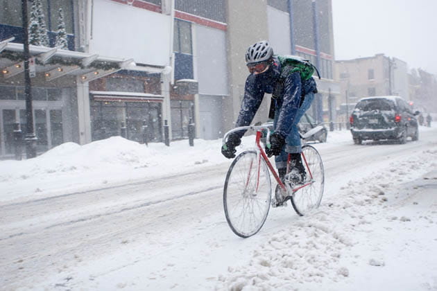 Ein Radfahrer fährt auf einer zugeschneiten Straße in der Stadt.