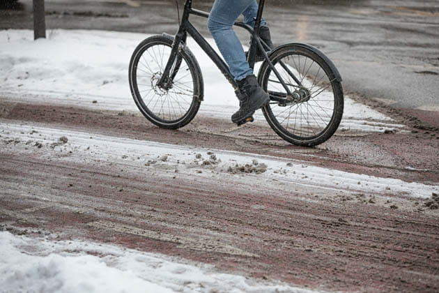 Ein Radfahrer fährt auf einem durch Schnee matschig gewordenen Radweg.