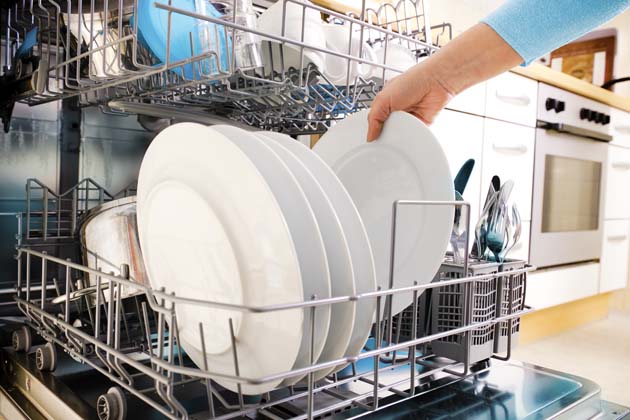 Nahaufnahme von Händen beim Einräumen von Geschirr in die Spülmaschine 