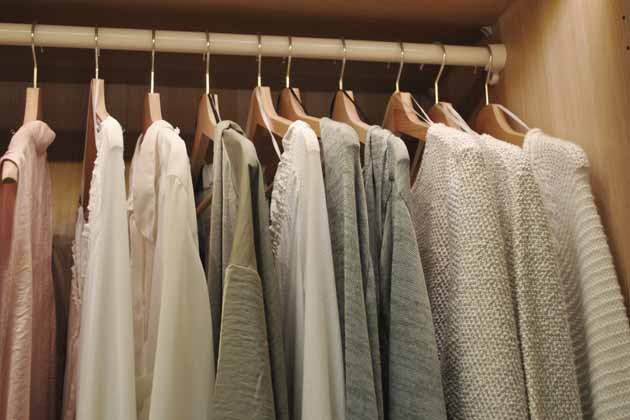 Ein paar Kleidungsstücke hängen ordentlich aufgehängt im Kleiderschrank. 