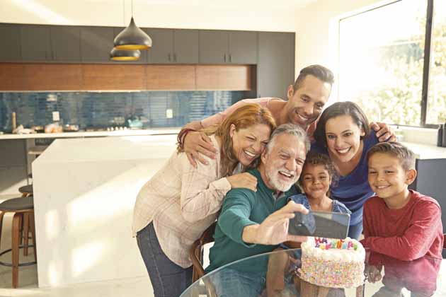 Eine Familie feiert Geburtstag mit Torte und kommt zusammen für ein Selfie.