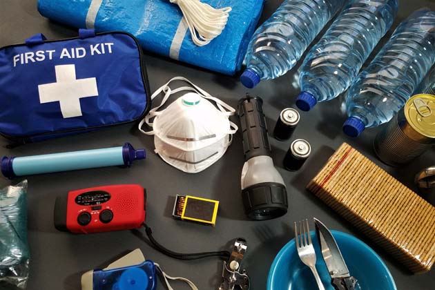 Eine Notfallversorgung als Vorbereitung auf ein Hochwasser: Erste-Hilfe-Set, Maske, Taschenlampe, Trinkwasser in Wasserflaschen, Taschenlampe, Batterien, Radio, Streichhölzer etc.