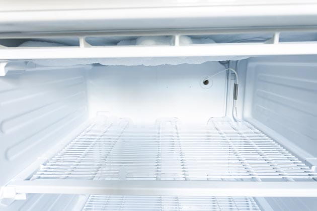 Das silberne Kühlgerippe im Gefrierschrank ist von einer Eisschicht bedeckt.