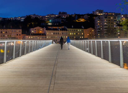 Zwei Menschen gehen über eine beleuchtete Brücke