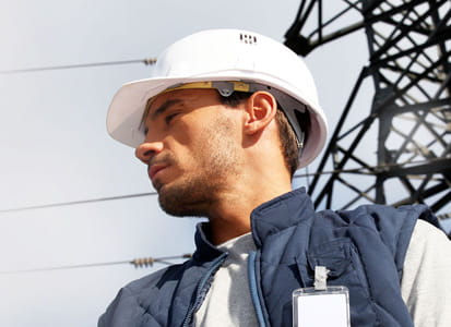 Mann mit weißem Helm vor Strommast