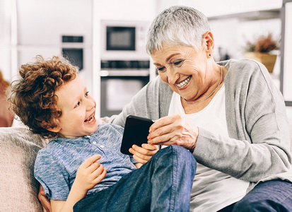 Großmutter und Enkel spiele auf dem Sofa am Smartphone