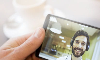 Handy zeigt jungen Typ und wird vor den Hintergrund einer Kaffeetasse gehalten